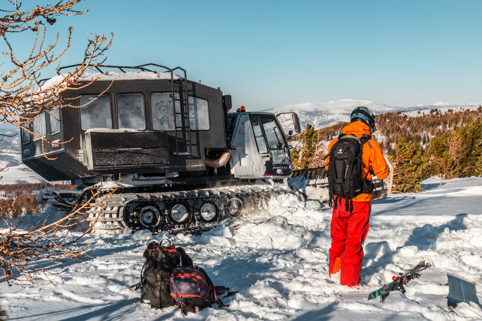 Snowcat and a snowboarder on catskiing in Ridder, Altai mountains